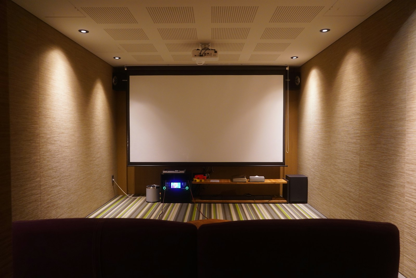 A dedicated home cinema with a projection screen and warm wall lighting