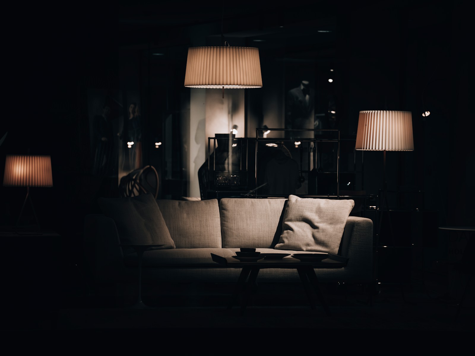 A living room at night, sofa lit by warm table and pendant lamps